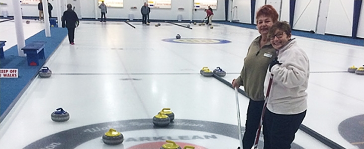 Curlers on curling rink ice holding brooms