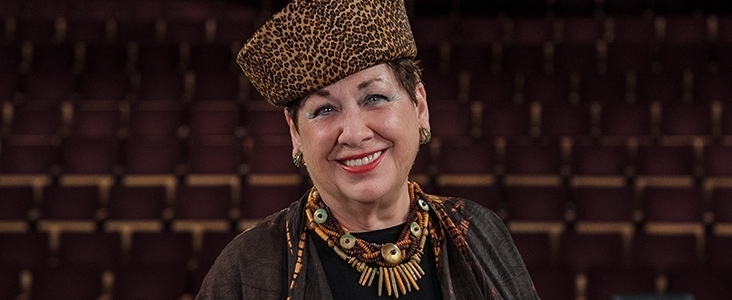 Photo of Carol Watamaniuk smiling in front of rows of seats at the Arden Theatre.