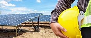 A work holds their hard hat next to a newly built solar array