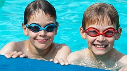 Two boys smile in the pool at Grosvenor Outdoor Pool in Saint Albert, Alberta