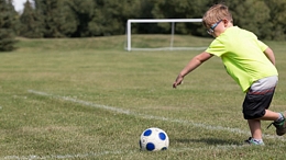 boy kicking a soccer ball outside