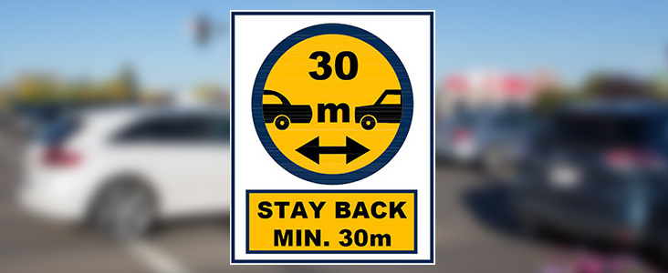 Photo of traffic that is blurry with a sign on top that says Stay back minimum of 30m