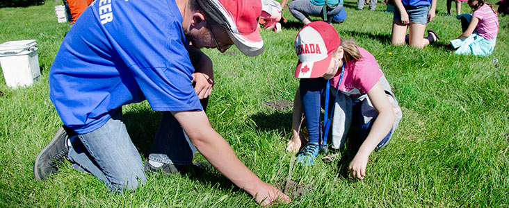 Photo from Spruce Up with people helping to plant trees along the river