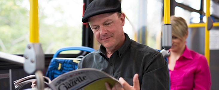 Photo of a man sitting on a bus reading the newspaper