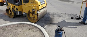 A steamroller levels and compresses fresh asphalt