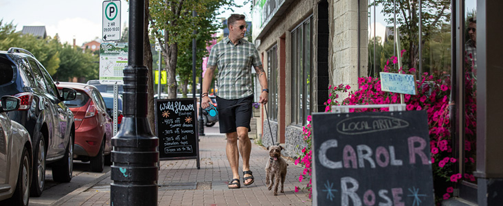 A man browses boutiques with his dog in the Perron District